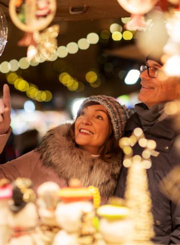 Glückliches Paar erkundet den beleuchteten Weihnachtsmarkt.