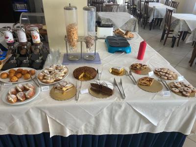 Dessert buffet with cakes, croissants, and cereals.