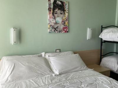 Camera da letto con letto matrimoniale, letti a castello e quadro colorato.