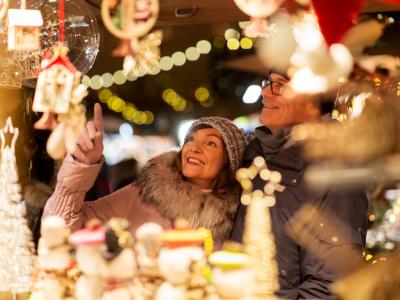 Coppia felice esplora il mercatino di Natale illuminato.