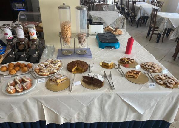 Dessert buffet with cakes, croissants, and cereals.