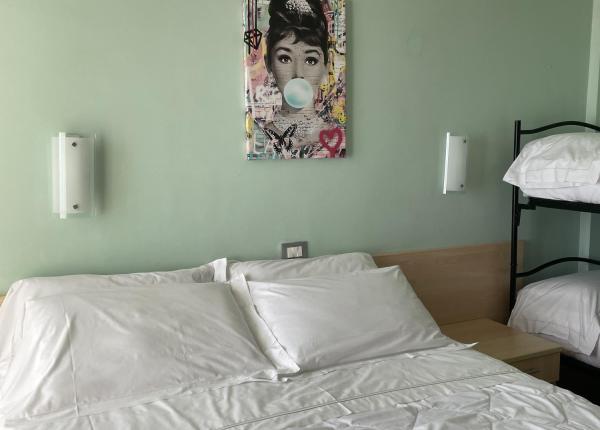 Bedroom with double bed, bunk beds, and colorful painting.