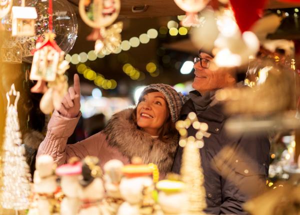 Coppia felice esplora il mercatino di Natale illuminato.