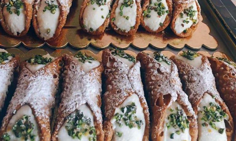 Sizilianische Cannoli mit Ricotta und Pistazien auf goldenem Tablett.