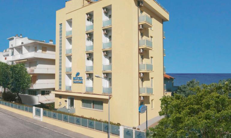 Hôtel moderne près de la mer avec balcons et enseigne bleue.