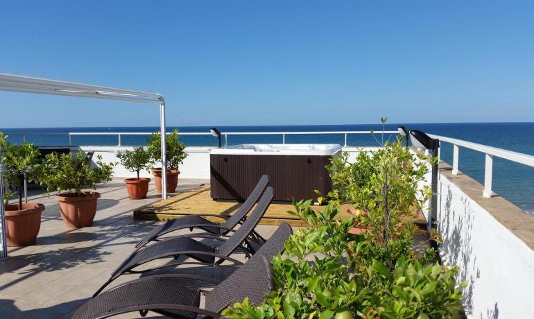 Seaside terrace with jacuzzi and sun loungers.