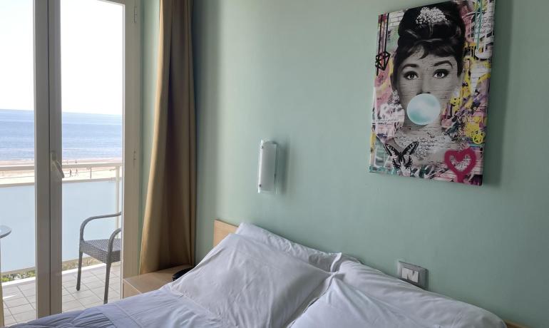 Camera con vista mare, letto matrimoniale e quadro moderno.