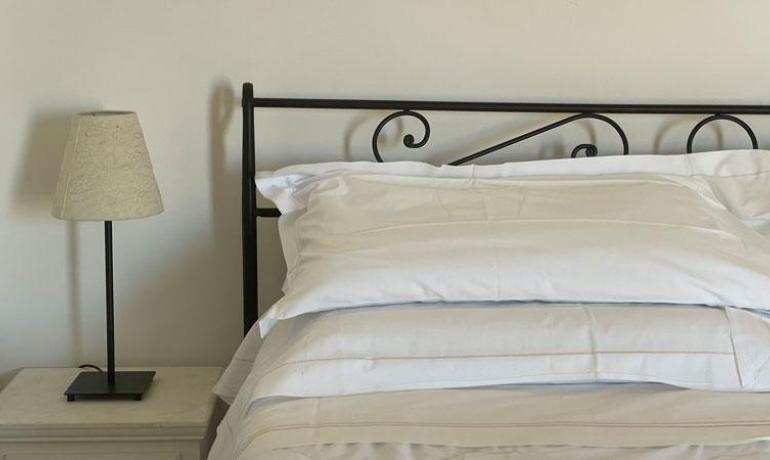 Bed with white sheets and lamp on nightstand.