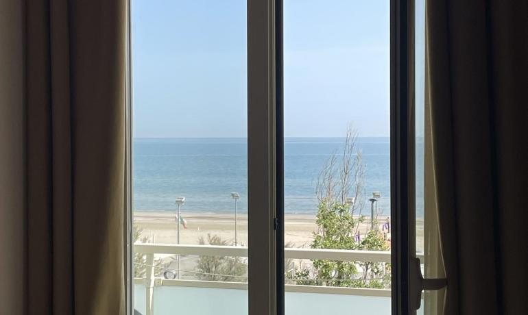 Blick aus dem Fenster auf einen Strand mit ruhigem Meer.