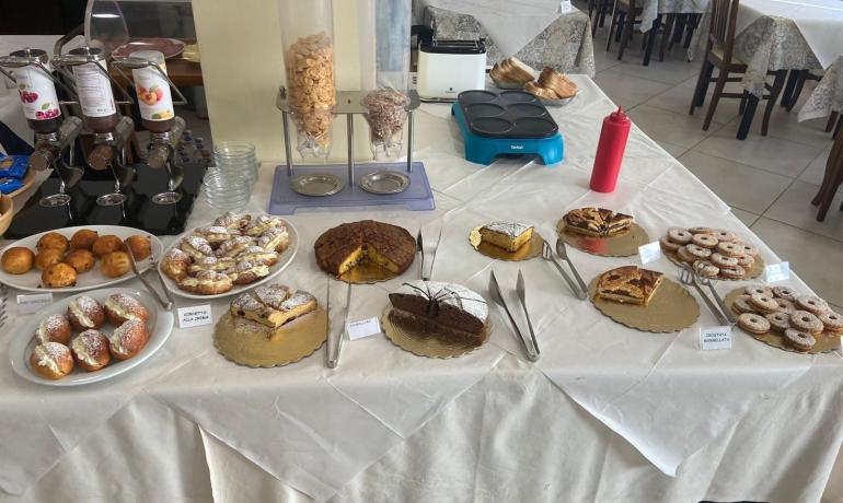 Dessert buffet with cakes, croissants, and cereals.