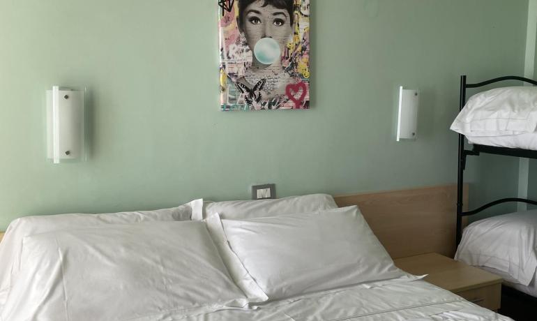 Camera da letto con letto matrimoniale, letti a castello e quadro colorato.