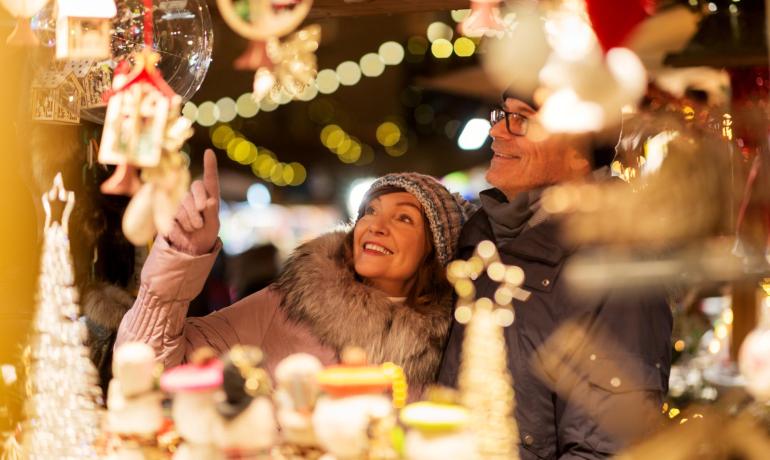 Coppia felice esplora il mercatino di Natale illuminato.