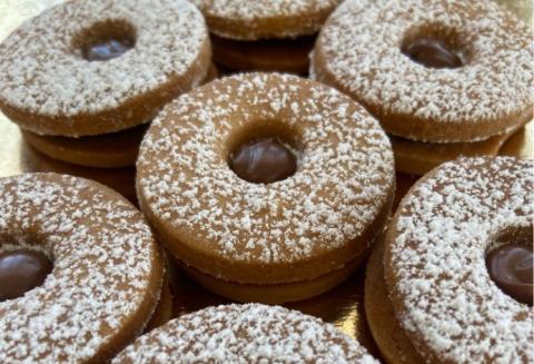 Biscotti al cioccolato con zucchero a velo, disposti in cerchio su un vassoio dorato.